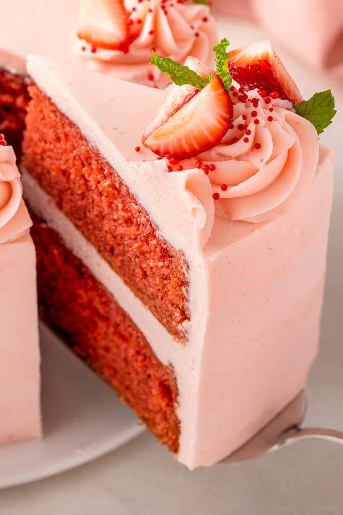 A moist homemade cake is flavored with fresh strawberry puree and topped with pink frosting.