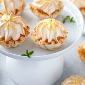 Bite-sized lemon meringue pie servings on a cake plate.