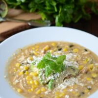 Creamy Corn and Chicken Soup with Roasted Poblano in white bowl, garnished with avocado slices.