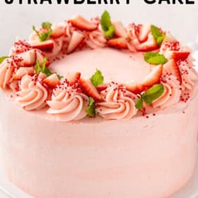 A layered strawberry cake is topped with fluffy buttercream.