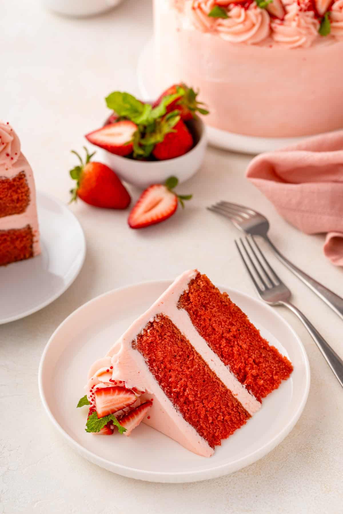 A slice of fresh strawberry cake is presented on a white plate.