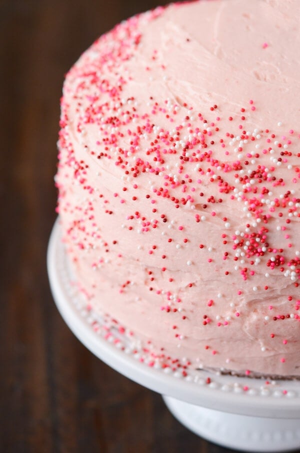 Close up of strawberry frosted cake on a white cake platter