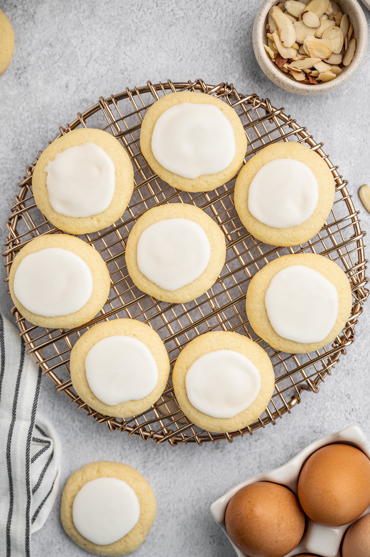 Almond meltaway cookies on a circular dish. Eggs, almonds, and a cloth napkin are arranged artistically around the table.