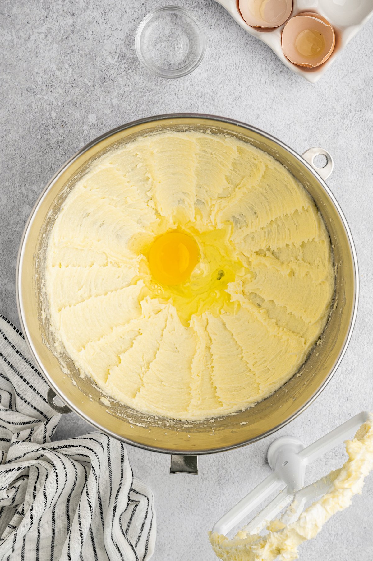 Creamed butter and sugar in a mixing bowl with an egg cracked in the center.