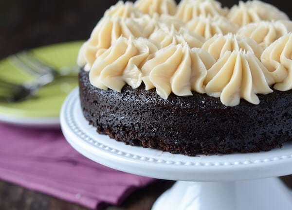 A Dark Chocolate Guinness Cake with Dollops of Bailey's Frosting on a White Cake Platter