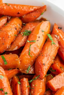 Close-up shot of candied carrots in a white bowl.