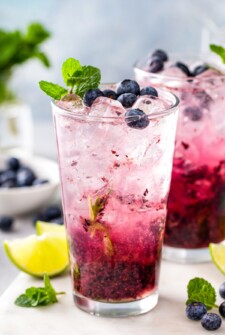 Glass of blueberry mojito with a mint leaf on top.