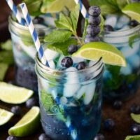 Blueberry Mojitos with limes and blueberries on a dark surface