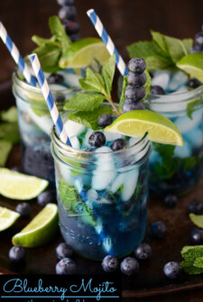 Blueberry Mojitos with limes and blueberries on a dark surface