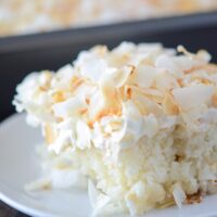 A close up shot of a big slice of Coconut Sheet Cake