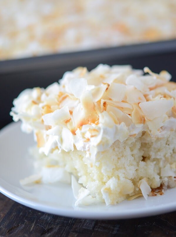 A close up shot of a big slice of Coconut Sheet Cake