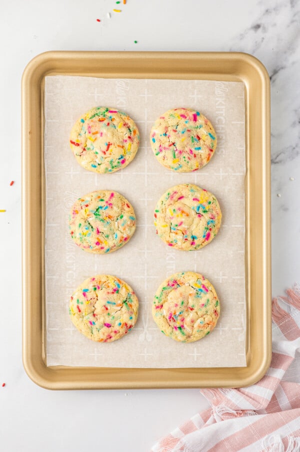 A baking sheet with six baked funfetti cookies on it.
