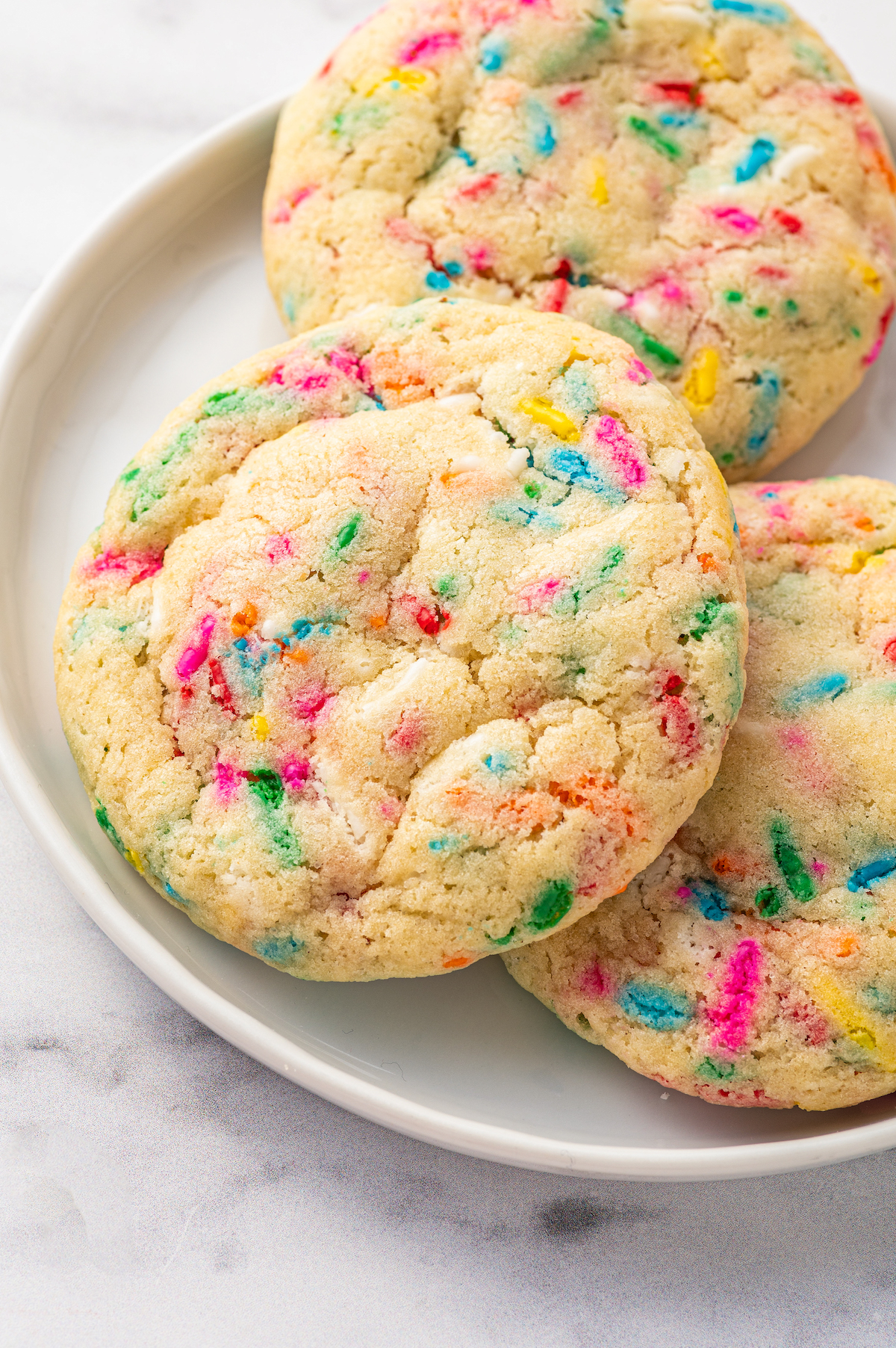 Funfetti cookies overlapping on a small plate.