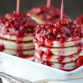 Stacks of Homemade Pancakes with Raspberry Sauce on a white platter.