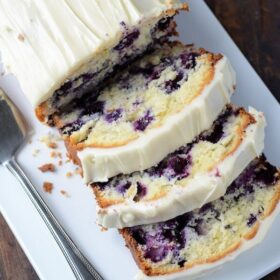 Blueberry Lime Cream Cheese Pound Cake sliced on a white platter.