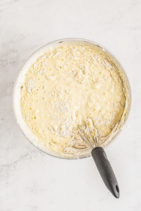 Textured pancake batter in a mixing bowl with a whisk.