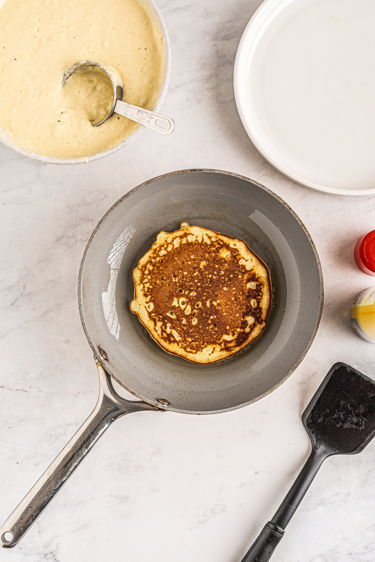 A pancake cooking in a skillet.