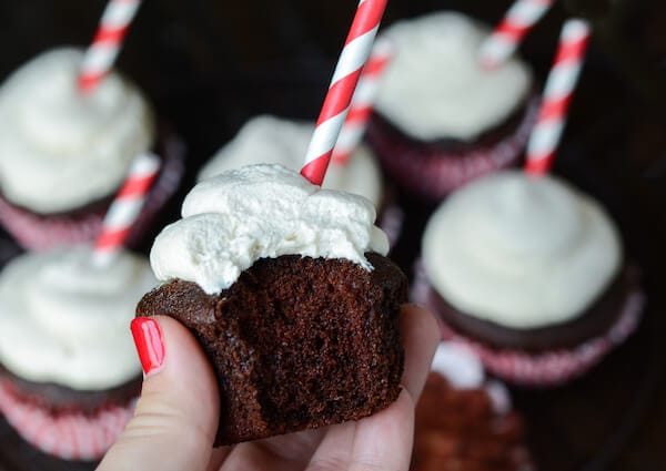 Root Beer Float Cupcakes with red and white straws and a bit taken out of one of the cupcakes.