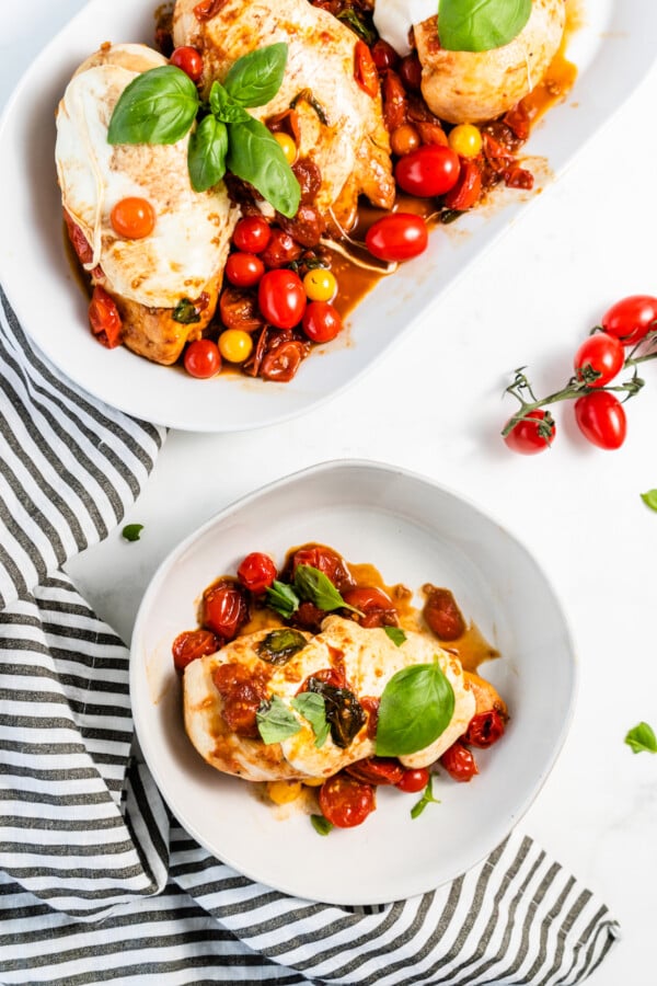 Plate of caprese chicken with cherry tomatoes.
