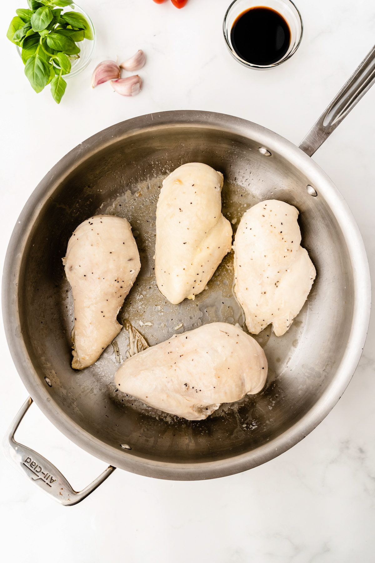 Four chicken breasts in a pan.