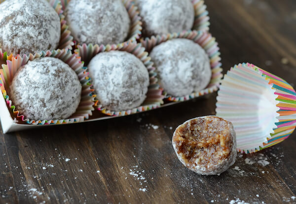Seven Almond Date Truffles Coated in Sugar on a Wooden Table