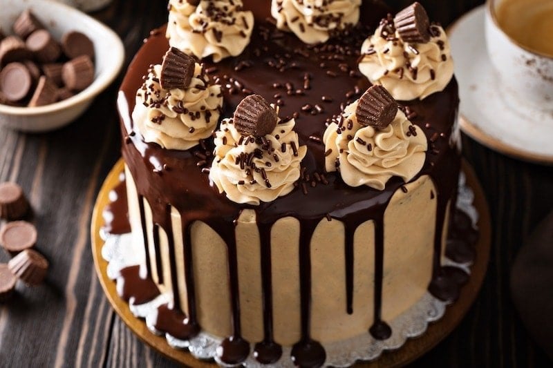 Chocolate and Peanut Butter Dream Cake -- it tastes like a giant Reese's cup in cake form! Start with a crazy moist, rich chocolate three layer cake with creamy peanut butter frosting and top it with a sweet dark chocolate glaze! #Chocolate #Cake #PeanutButter