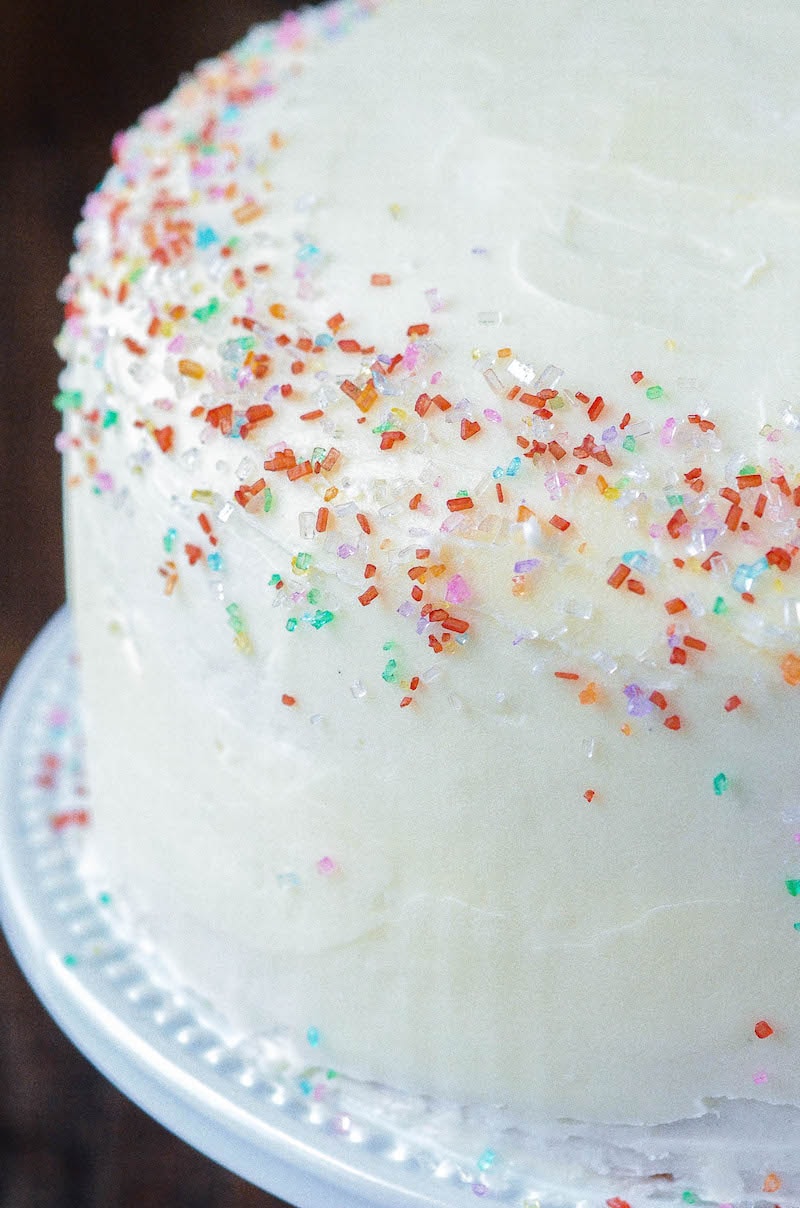 Close-up of a white frosted cake with multicolored sugar sprinkles decorating the edge