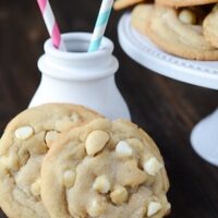 Two White Chocolate Macadamia Nut Cookies set up against a small white ceramic milk jug.