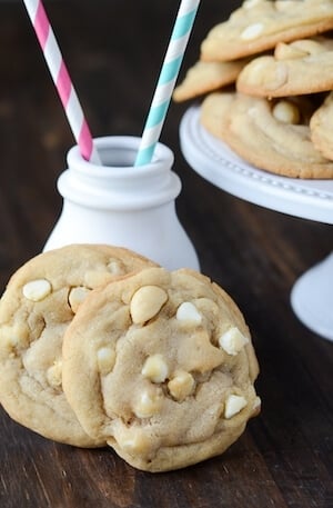 Two White Chocolate Macadamia Nut Cookies set up against a small white ceramic milk jug.