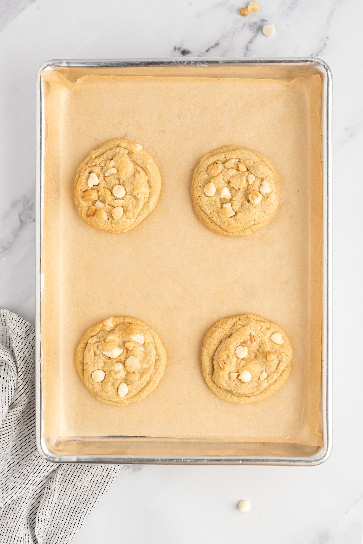 Baked white chocolate cookies on a baking sheet.