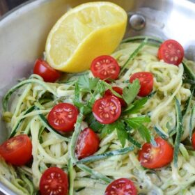 Photo collage of zoodles tossed in a lemon cream sauce, with cherry tomatoes and a half of a lemon.