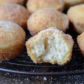 Baked Mini Doughnut Muffins on a baking rack - one muffin has a bite taken out