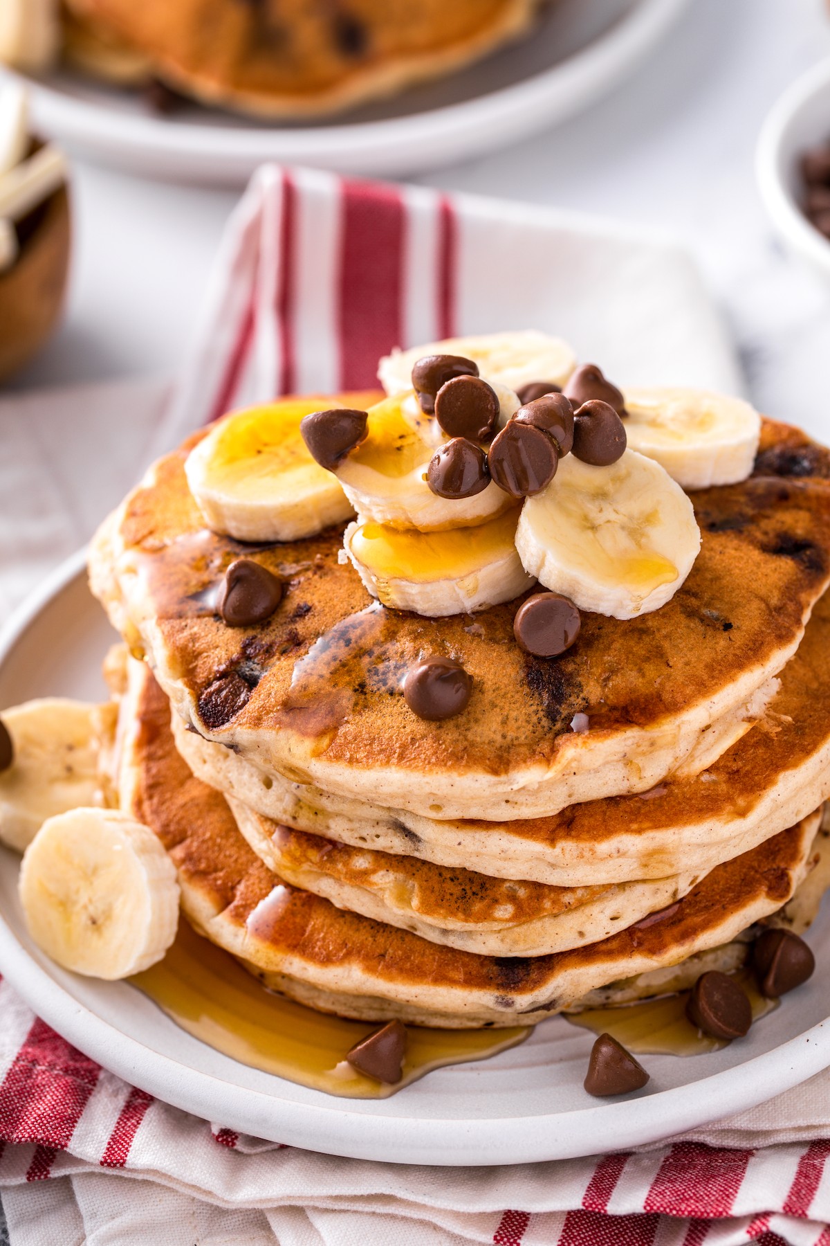 A plate of banana chocolate chip pancakes topped with sliced bananas and chocolate chips