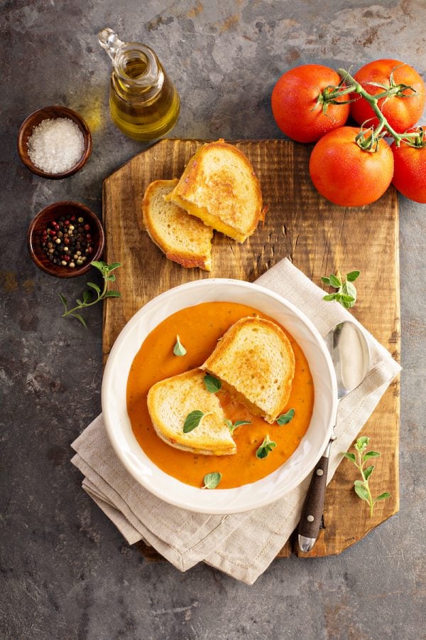 Creamy tomato soup with a grilled cheese sandwich in the soup bowl.