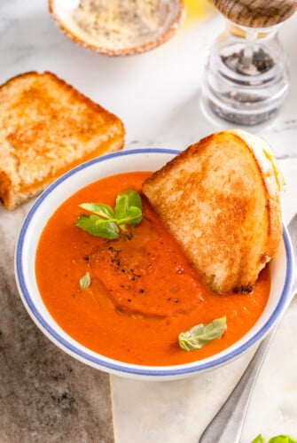 A half a grilled cheese on sourdough dipped into copycat Panera tomato soup recipe.