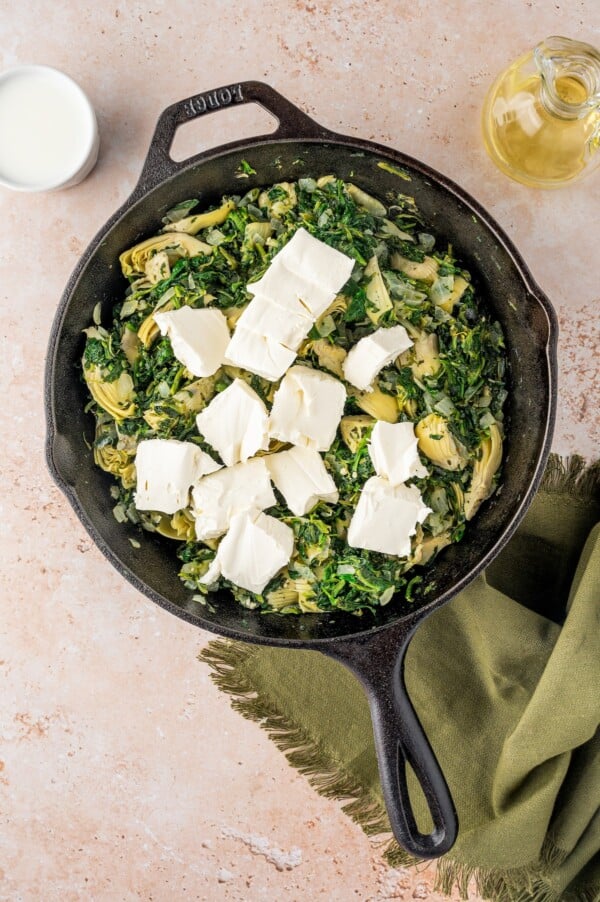 Adding cream cheese to a skillet.