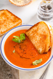 A half a grilled cheese on sourdough dipped into copycat Panera tomato soup recipe.