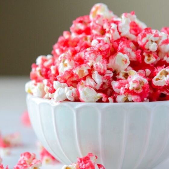 Hot Tamale Popcorn in a white bowl and scattered popcorn on a white surface