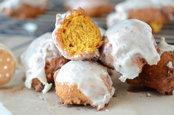 Pumpkin Fritters with Cinnamon Glaze piled together and one has a bite missing