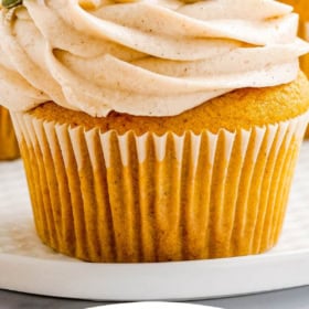 Up close image of pumpkin cupcakes on a white plate with wording on top for Pinterest.