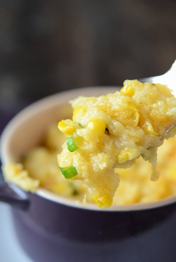 Spoonful of Southern Corn Pudding in a purple baking dish