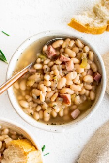 Bowl of ham and bean soup with fresh herbs.