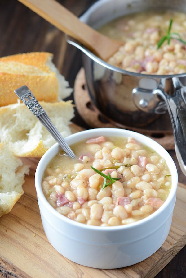 Rosemary Ham and Bean Soup in a white bowl with a spoon and bread