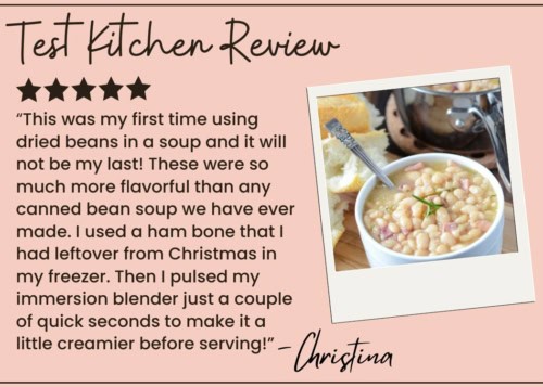 A review titled Test Kitchen Review features a five-star rating, a quote praising homemade ham and bean soup, and a photo of a bowl of creamy white bean soup with a spoon, sliced bread, and savory ham pieces.