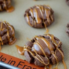 Turtle Chocolate Cookies in rows on a baking sheet topped with a caramel drizzle