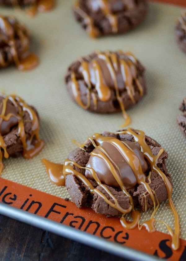 Turtle Chocolate Cookies in rows on a baking sheet topped with a caramel drizzle