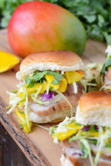 Pork Tenderloin Sliders with Spicy Mango Slaw on a wooden board.