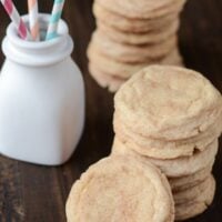 Two stacks of snickerdoodle cookies next to a white jar with straws