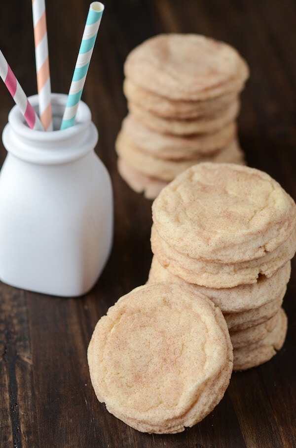 Two stacks of snickerdoodle cookies next to a white jar with straws