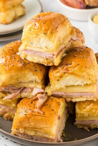 Ham and cheese sliders stacked on a plate.